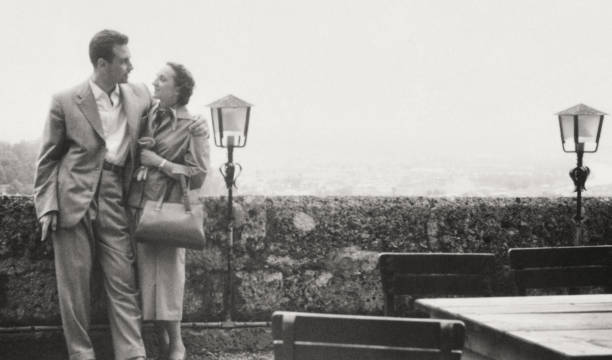 Young couple standing close to a sidewalk cafe. 1958. Sepia Toned.
