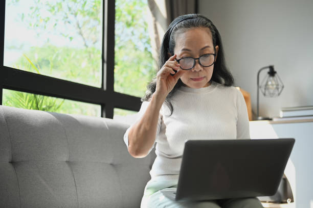 istock Middle age woman touching her glasses looking attentively at laptop computer. 1851781750