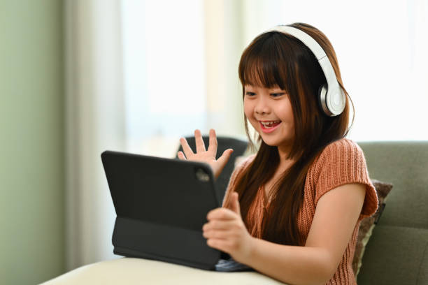 istock Smiling Asian girl in headphone studying virtual course with remote tutor at home. 1851782881