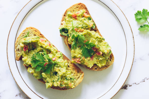 istock Toasts with guacamole on white plate on marble background. 1851786103