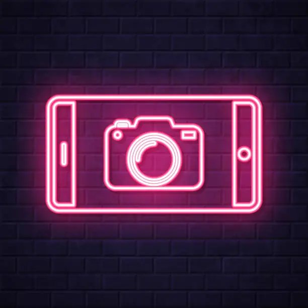 Vector illustration of Smartphone with camera. Glowing neon icon on brick wall background