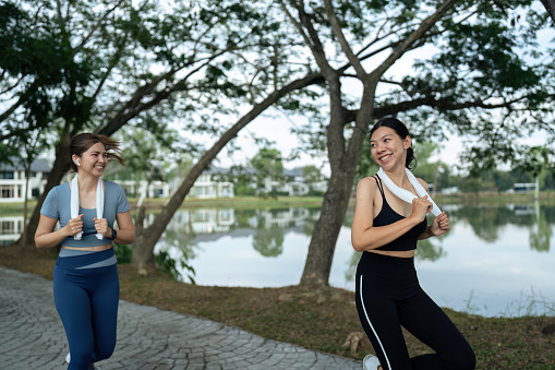 Two happy women going for sunrise running. Women in track suits running at park.