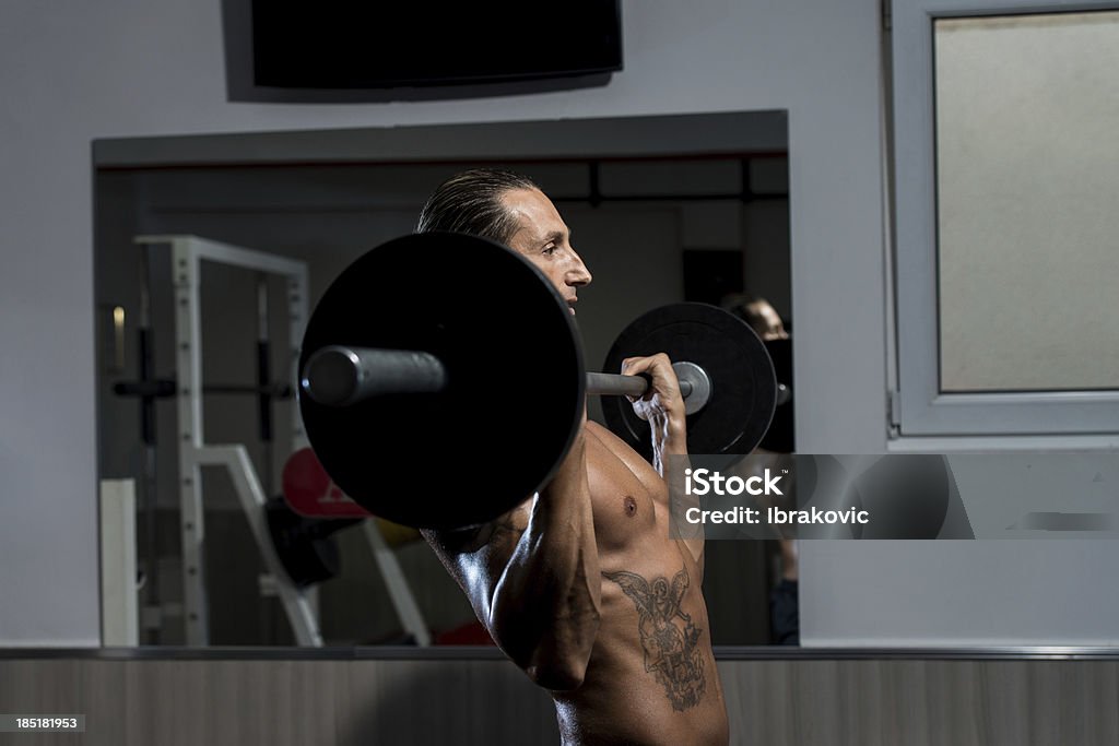 Macho Man Lifting Weights With Barbell Men In The Gym Performing Biceps Curls With A Barbell 30-39 Years Stock Photo