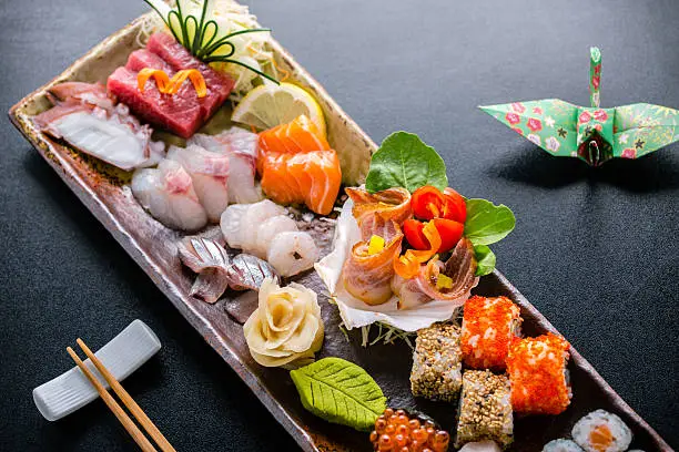 Close up picture of "Sashimi & Sushi plate" with: tuna fish, swordfish, salmon, nigiri, wasabi, zenzero, uramaki, futomaki & origami.