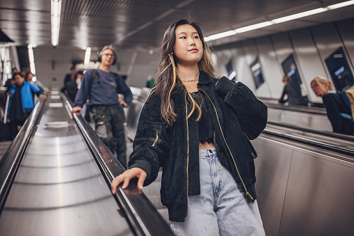 Young Asian woman riding on escalator in subway station in Vienna.