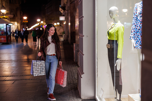 Step into a world of fashion reverie as a young woman delves into dreams and inspiration through window shopping at night