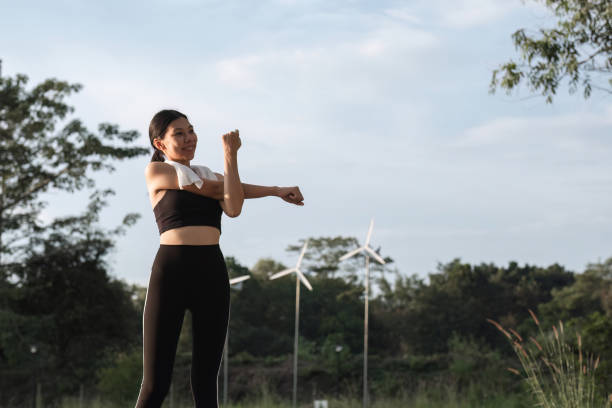 mulher asiática bonita em roupas esportivas alongando-se antes de correr ou correr no parque. cuidar da sua saúde e ser forte - aquecimento físico - fotografias e filmes do acervo