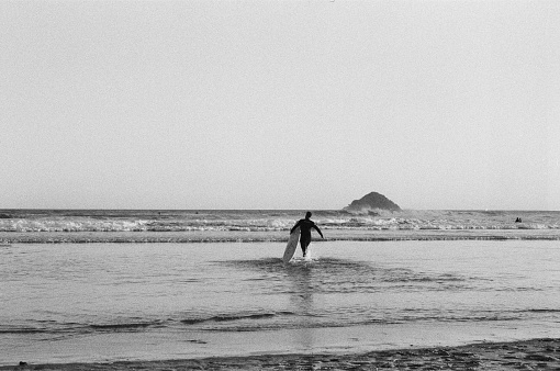 Surfer running towards the sea on the coast of Brazil. Image taken in film, black and white. high contract, idylic