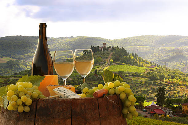 Bottle of wine, cheese and grapes overlooking Chianti view White wine with barrel on vineyard in Chianti, Tuscany, Italy siena italy stock pictures, royalty-free photos & images