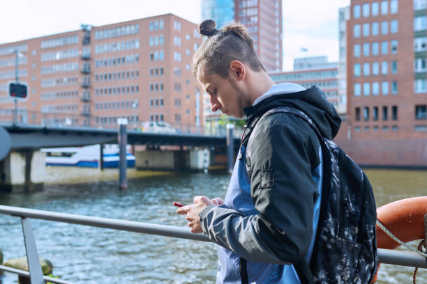 istock Fashionable young male with backpack using smartphone outdoors in city 1851880970