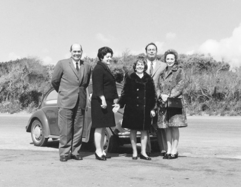 Group of People standing close to a vintage car. 1960.