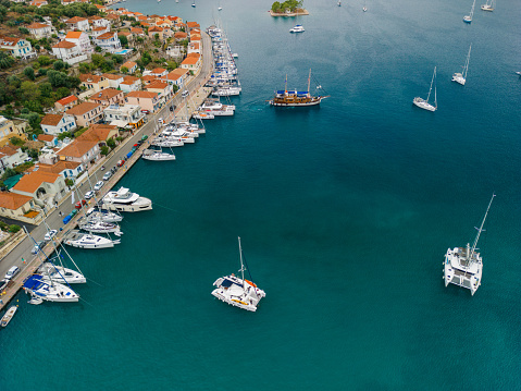 Aerial view of sailboats anchored in a beautiful bay of Vathi, Ithaca, Greece. There are small, traditional mediterranean houses near waterfront. It's a beautiful sunny summer day, the sea is blue, green and turquoise.