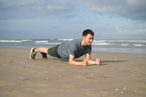 Close up shot of Asian man doing plank exercise at the beach