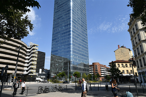 Lyon, France-07 18 2023: People passing nearby the Incity tower, a modern office skyscraper in the Lyon Part-Dieu financial district, France.