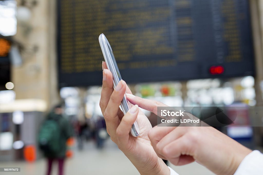 Mani di donna utilizzando il suo telefono cellulare in Stazione ferroviaria - Foto stock royalty-free di Adulto