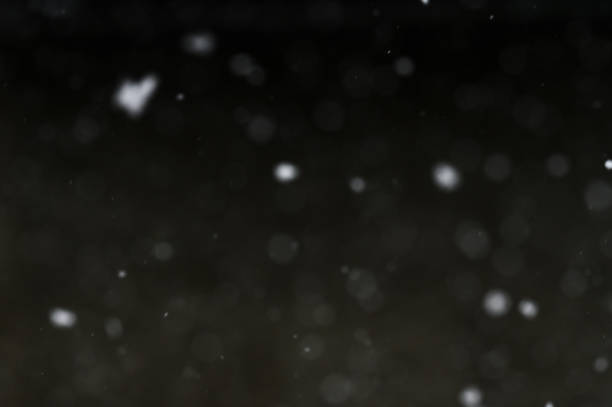 istock Bokeh of white snow on a black background. Snowfall - design element. 1851997453