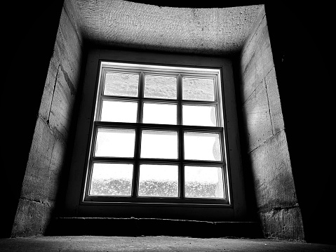 A toned monochrome image of a medieval window. Vignetting added.