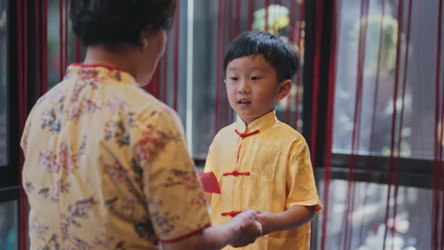 Chinese New Year Grandmother giving angpao red packet to grandson at home