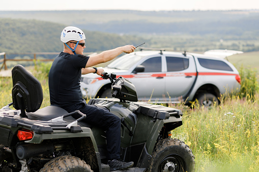 The rescuer, a beautiful athletic physique, rides an ATV in the middle of the field.