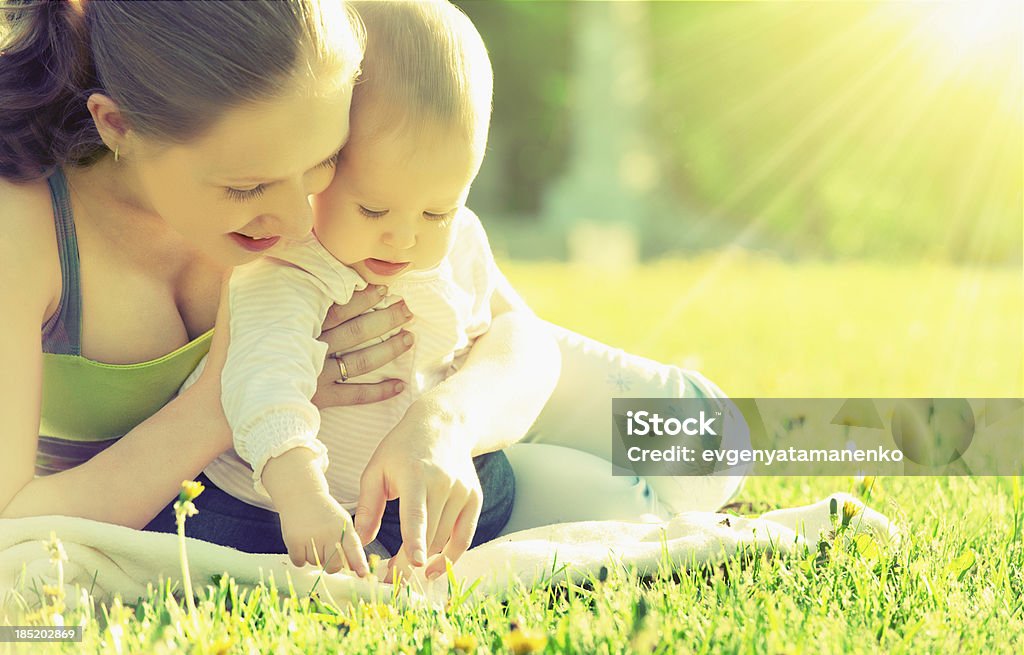 happy family. Mom and baby on meadow in summer  park happy family. Mom and baby resting in a meadow in the summer outdoors in the park Adult Stock Photo