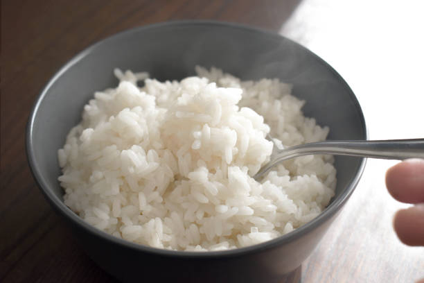 istock Cooked rice with steam on spoon in a bowl. Parboiled rice. 1852034391