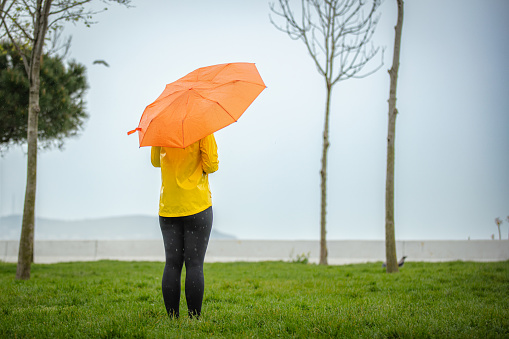 Young woman with orange umbrella in nature.