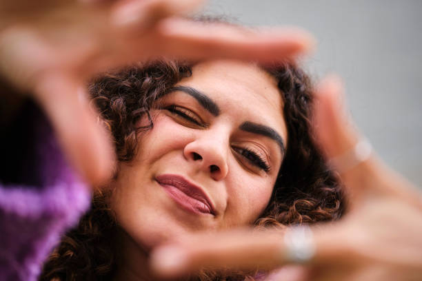 istock Young Spanish woman with curly hair wink and make a frame with hands. 1852054834