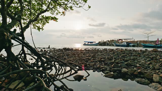 Fishing boats lying on stony barren beach of island with clouds moving above