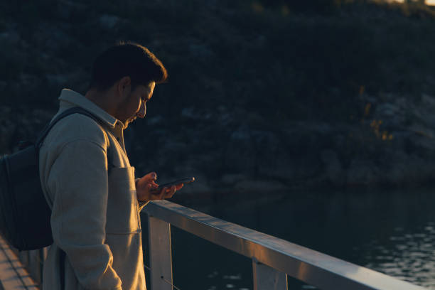 istock Latino man with a backpack looks at his mobile phone at sunset 1852062846