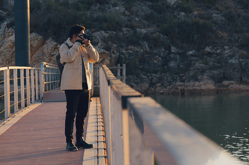 Latin photographer with a camera takes photos in a lagoon at sunset