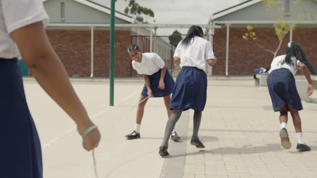 Schoolgirls skipping together and laughing during break time