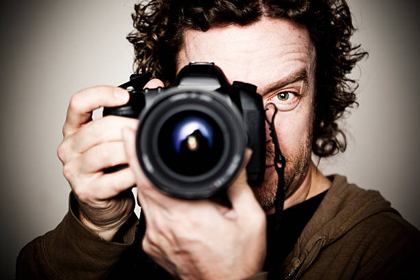 Surprised mature caucasian man holding digital camera about to photographing in the city in autumn