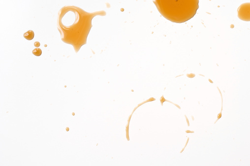 Spilled coffee drips on white table.