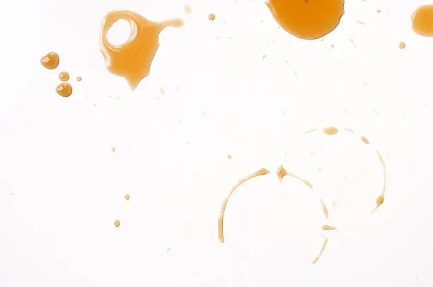 Spilled coffee drips on white table.