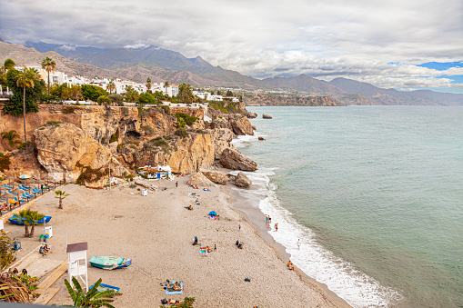 Nerja, Spain - 2nd November 2023: Elevated view of the Playa de la Calahonda, a beach on the Mediterranean Sea in Nerja, Costa Del Sol, Andalucia, Spain. People are  sunbathing on the beach or paddling at the edge of the Mediterranean Sea.