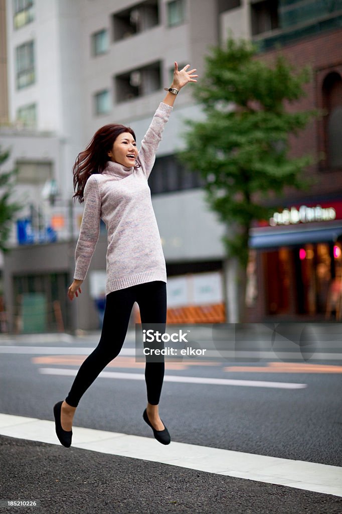 Jovem feliz mulher Japonesa Saltar para captura táxi em Tóquio - Royalty-free Saltar Foto de stock