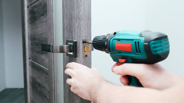 istock Handyman Fitting A New Door Using A Screwdriver At Home. Carpenter at lock installation with electric drill into interior wood door 1852106883