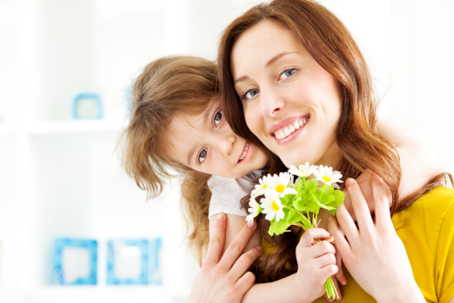 Portrait of an cute little girl, daughter, giving Bouquet of Daisies to her mother. Selective focus to cute little girl.