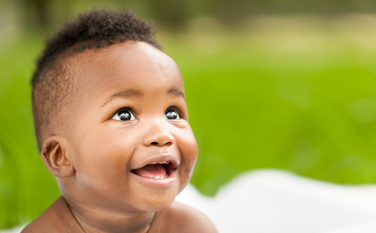 Cheerful little African American baby smiling while looking away. Horizontal Shot.