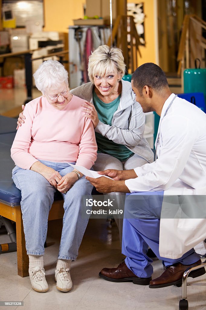 Mujer mayor y adultos hija hablando con fisioterapeuta - Foto de stock de Doctor libre de derechos