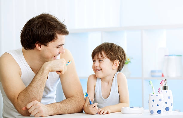 pai e filho escovar os dentes juntos. - human teeth child smiling family imagens e fotografias de stock