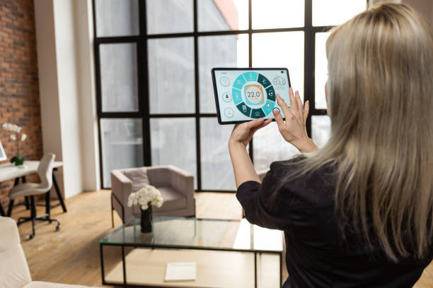 Iot Smart Home Concept - rear view of woman ask digital tablet to set temperature of air conditioner more higher by voice at home and all the electric meter in house getting energy-efficient. concepto de hogar inteligente de iot: vista trasera de la mujer pide a la tableta digital que establezca la temperatura del aire acondicionado más alta por voz en el hogar y todo el medidor eléctrico en la casa se vuelve energéticamente eficiente