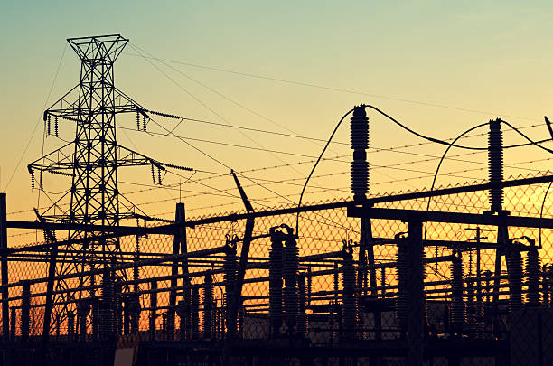 Electrical Substation Transformers, power lines and a transmission tower in post sunset glow. public utility stock pictures, royalty-free photos & images