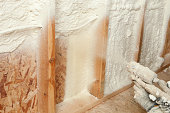 istock Construction Worker Spraying Expandable Foam Insulation between Wall Studs 185211977