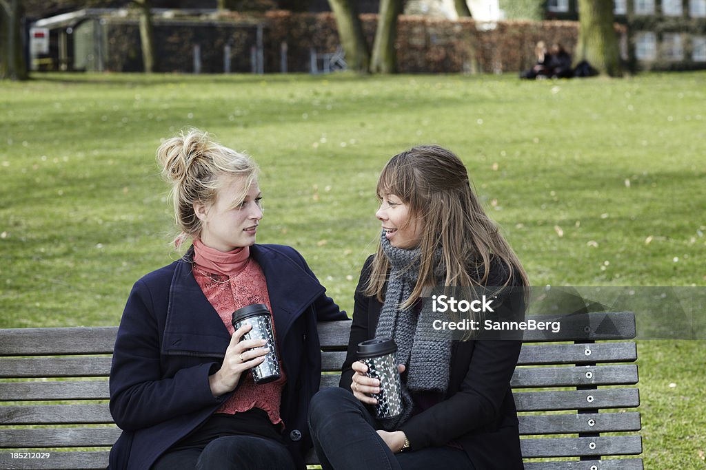 Dos mujeres college students sentado en un parque con café - Foto de stock de Adulto libre de derechos
