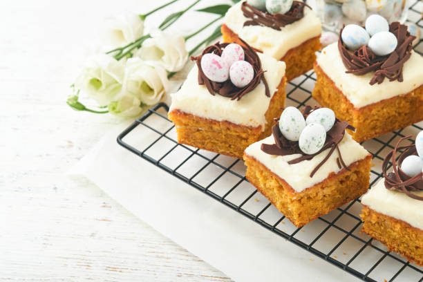istock Easter carrot cake bars decorated with chocolate nest and chocolate candy eggs blossoming cherry or apple flowers on rustic light wooden backgrounds. Easter holiday meal. Traditional Easter food. 1852120542