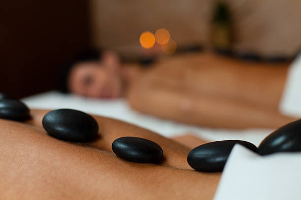 giovane coppia godendo la terapia lastone - spa treatment health spa massaging couple foto e immagini stock