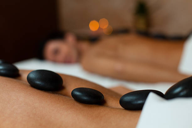Young couple enjoying lastone therapy Close-up view of warm stones on woman's back. Couple having lastone massage. hot stone massage stock pictures, royalty-free photos & images