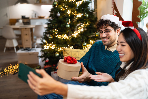 Love couple having a video call for Christmas while spending holidays at their cozy home.