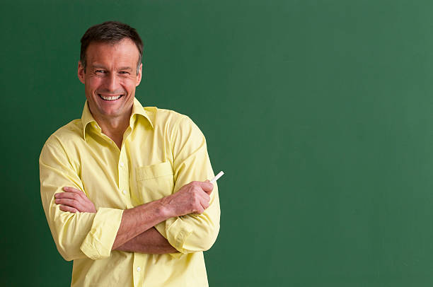 istock happy teacher with chalk at blackboard 185214014